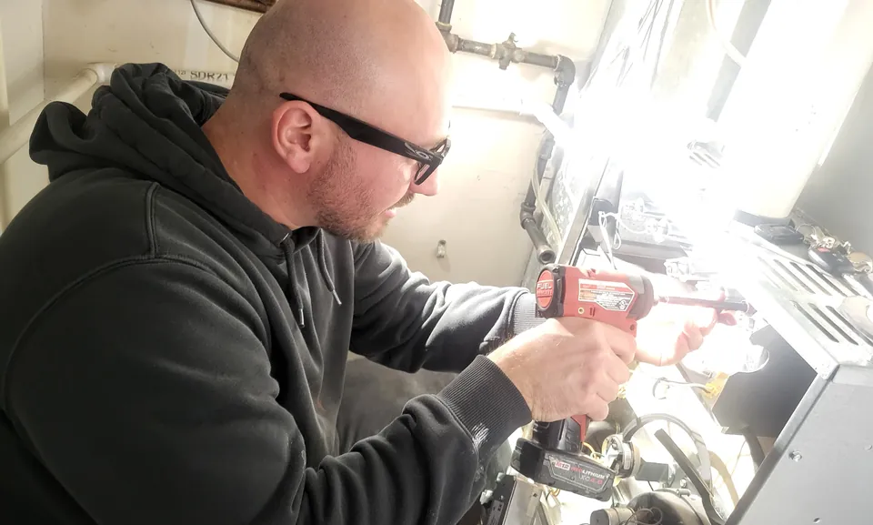 MH HVAC technician completing a seasonal furnace tune-up in a Worth, IL home