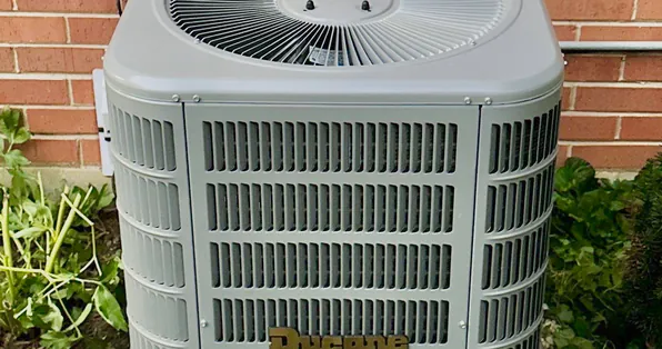 Close-up of a Ducane air conditioner condenser outside a brick home