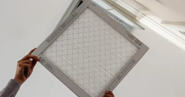 Pleated air filter being fitted into a ceiling return grille