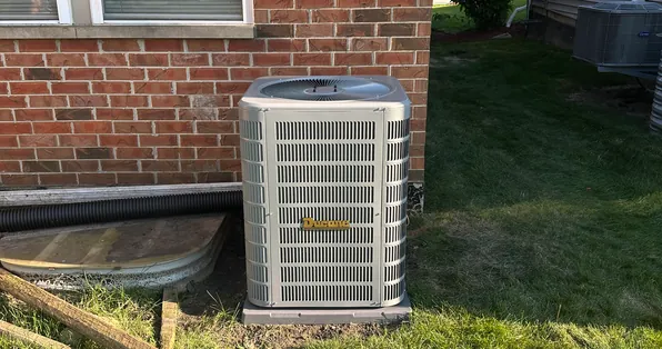 Central air conditioning condenser installed beside a brick home