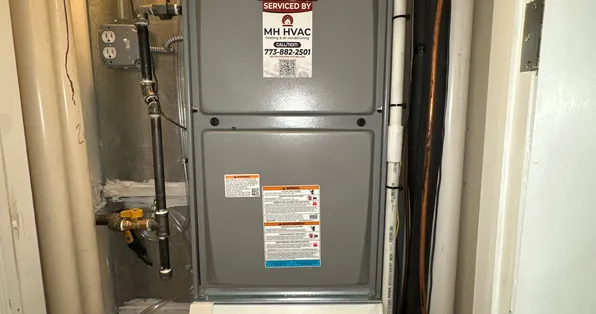Gas furnace with an MH HVAC service sticker, installed in a utility closet