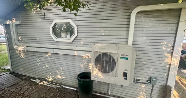 Fujitsu mini-split outdoor unit mounted on the siding of a home