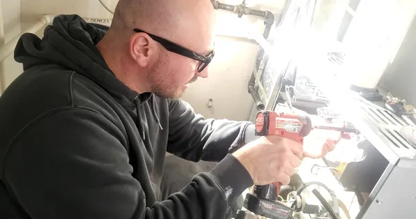 Technician using a power drill on an HVAC installation